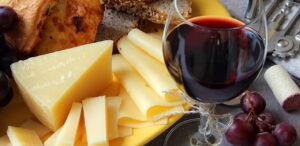 Tagliere di formaggi con calice di vino rosso e grappoli d'uva